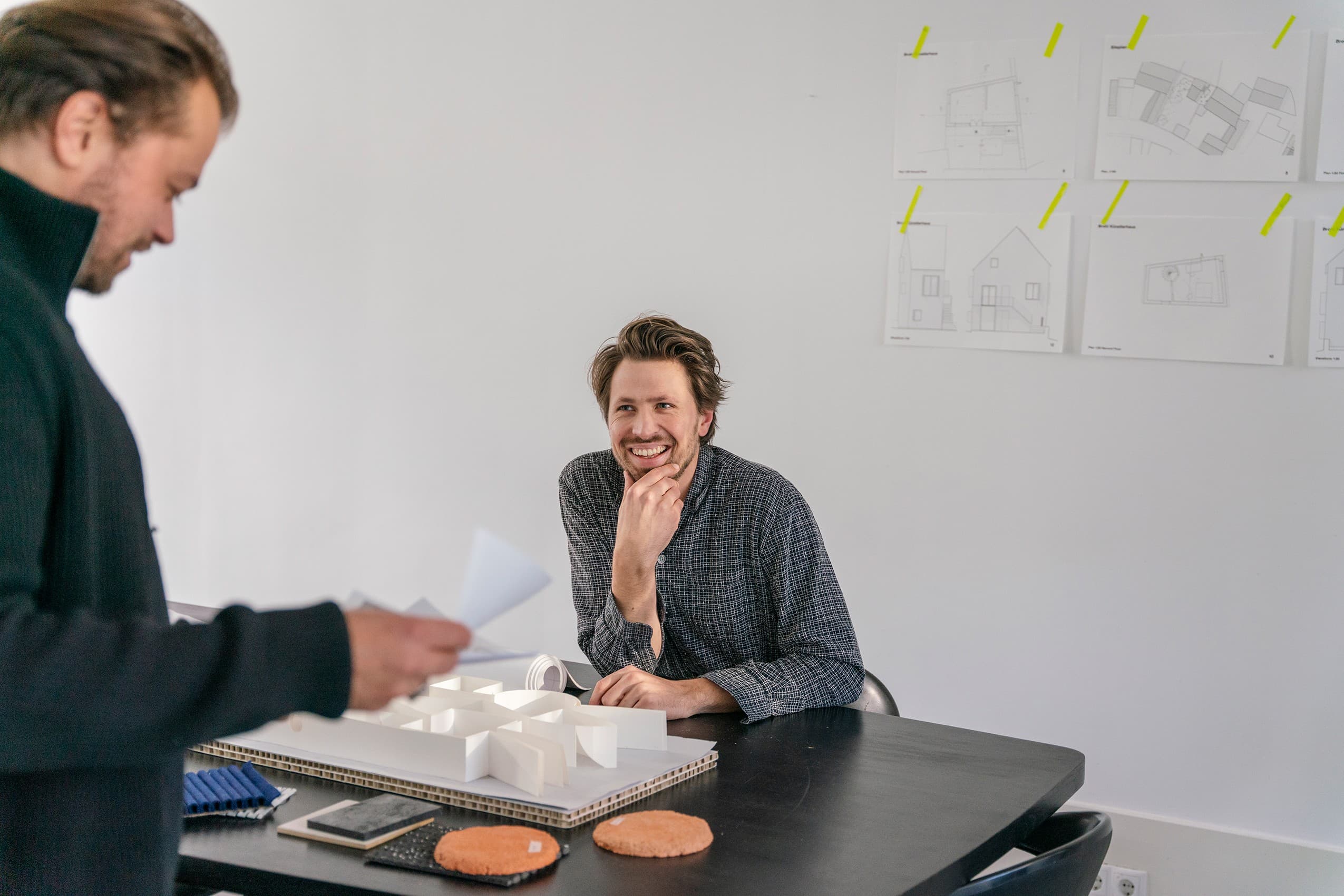 Twee professionals overleggen in een studio over een ontwerp en maquette.